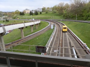 A PRT vehicle speeds along tracks bypassing Engineering station.