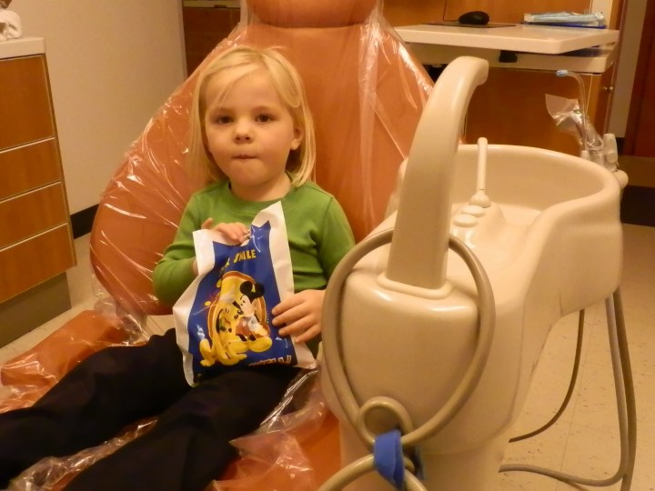 Fiona sits in the big orange chair with her bag of goodies as she gets ready to leave the dentist’s office.